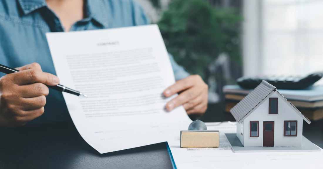 Contract and house miniature on table